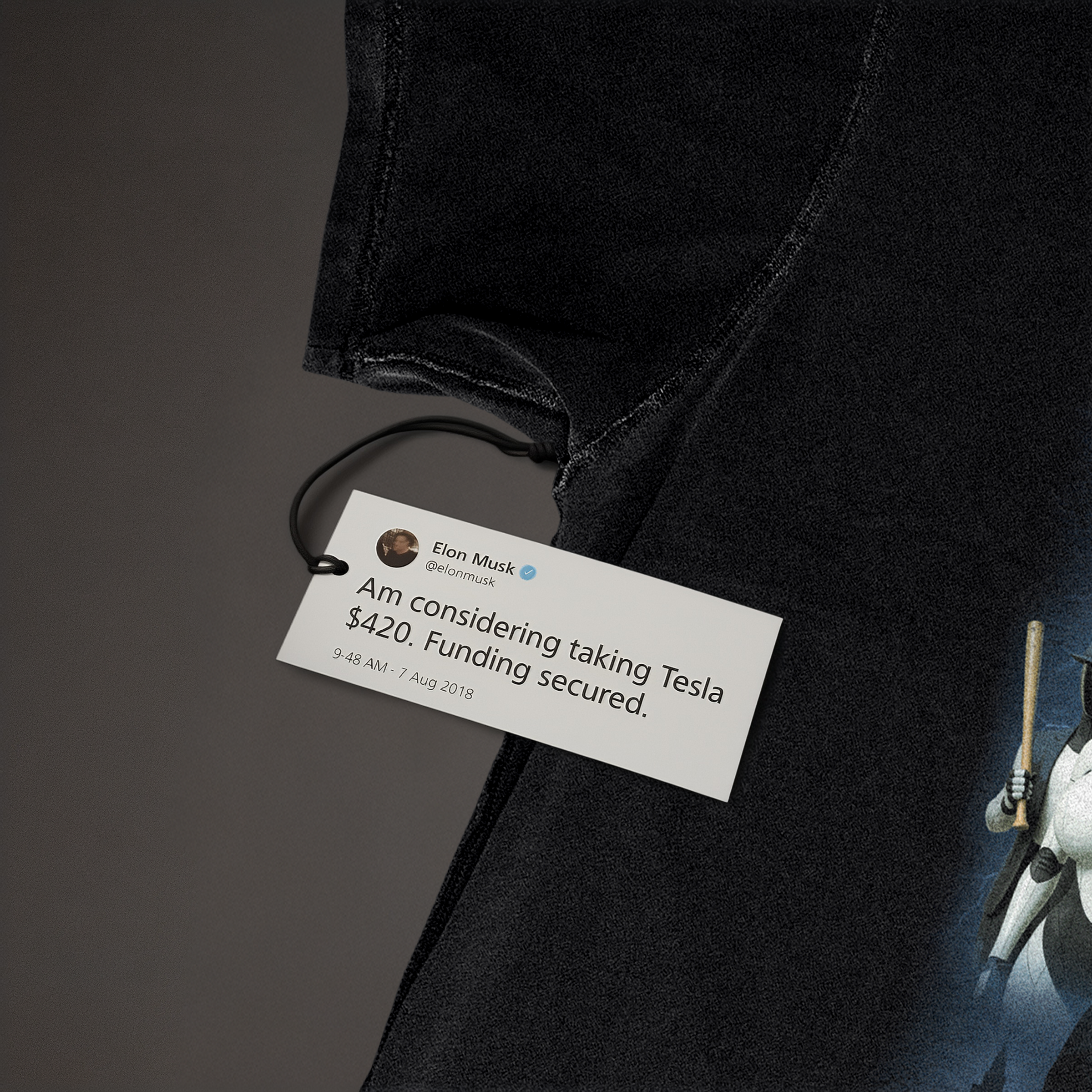 Close-up of Dogefather t-shirt fabric with printed tag featuring Elon Musk tweet 'Am considering taking Tesla $420. Funding secured'; humorous crypto meme tee detail