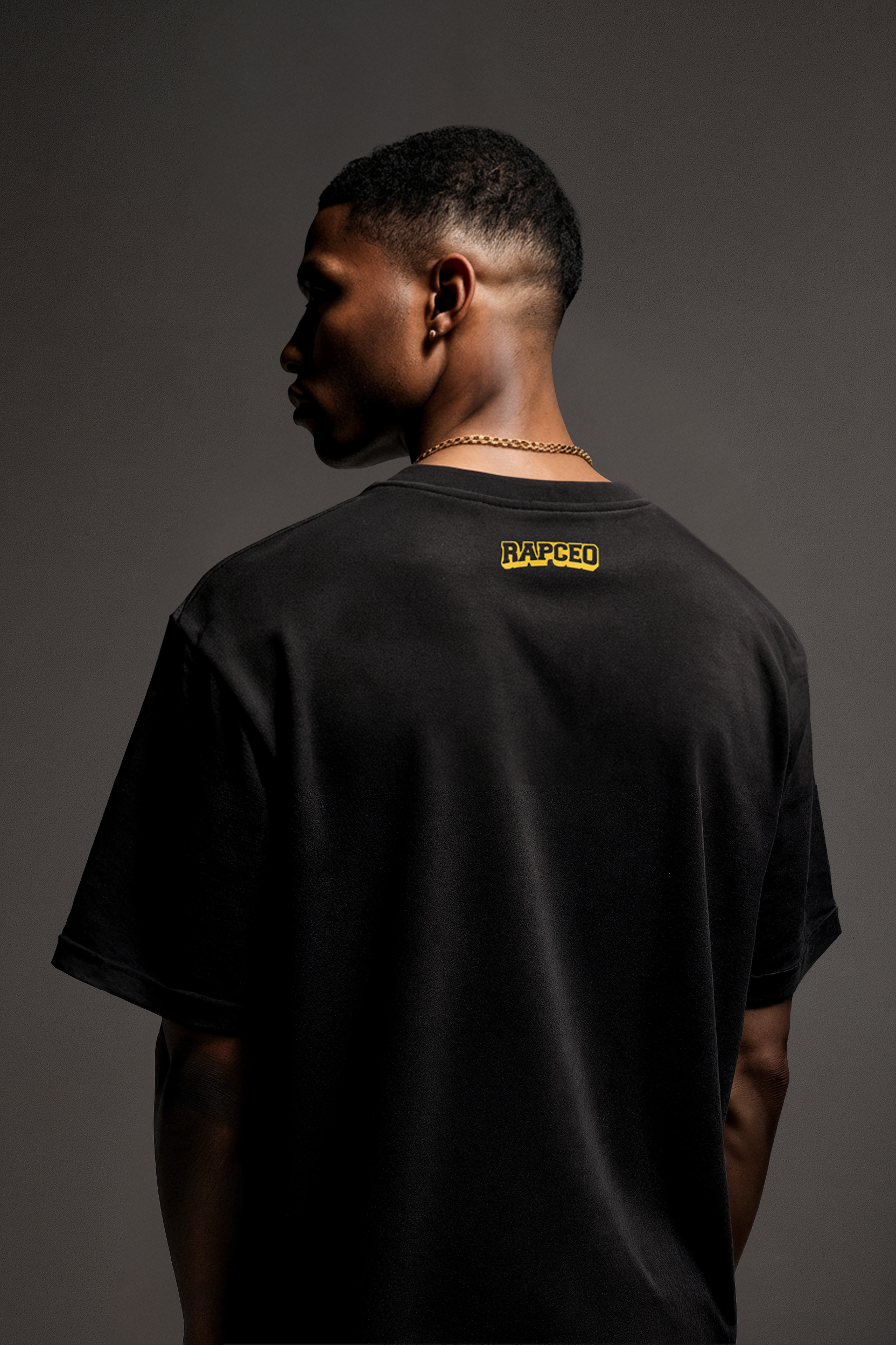 Back view of model wearing black Smoking Meats t-shirt with small RAPCEO logo printed in yellow near collar; minimalist branding