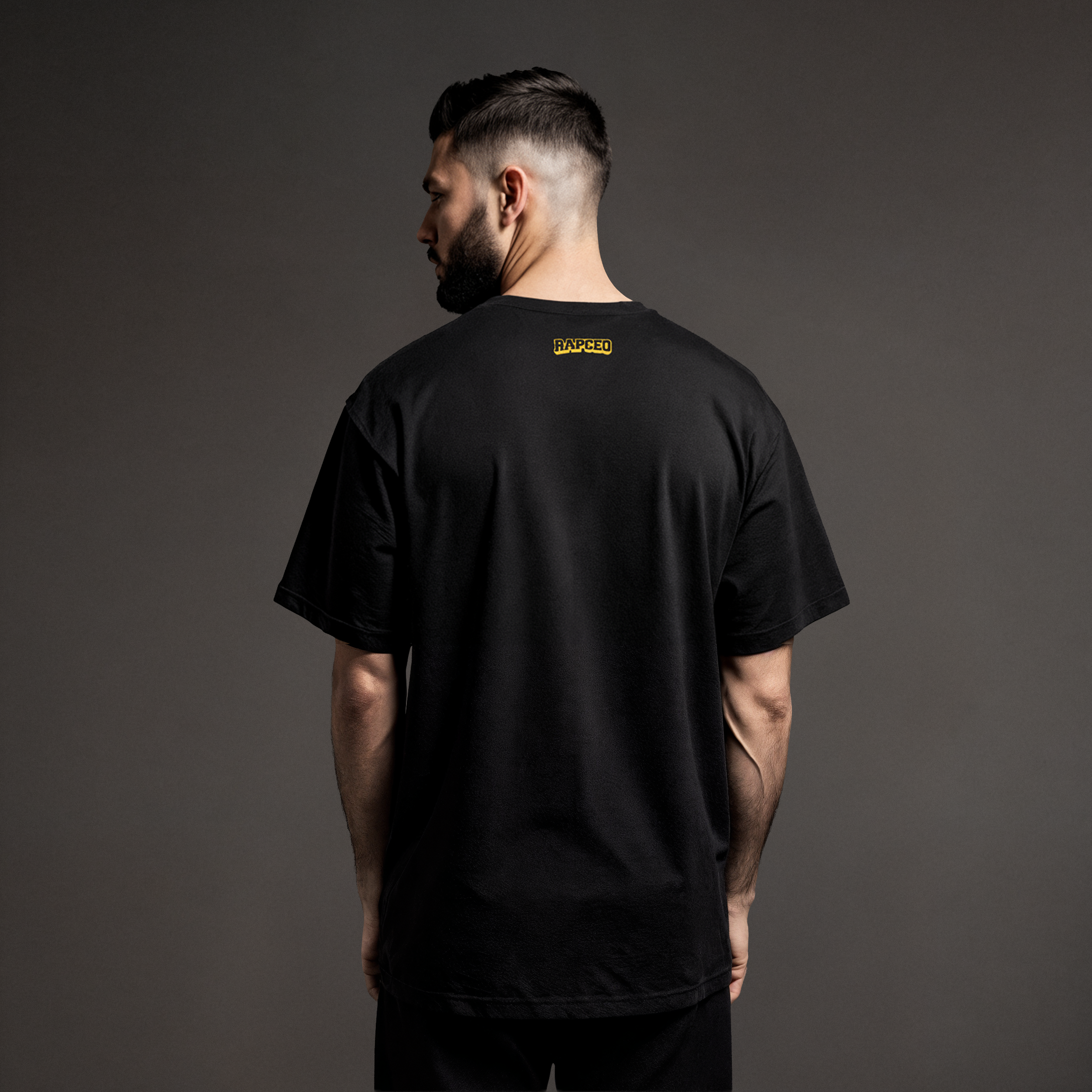 Rear view of model showing back of black tee with small yellow RapCEO logo at the nape.